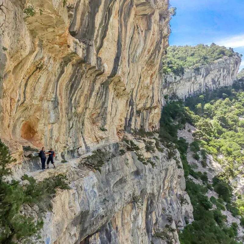 hiking the narrow ledge on the path s'istrada longa, located in the mountains of Baunei, Sardinia